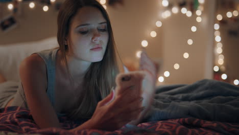 Schöne-Teenagerin-Liegt-Auf-Dem-Bett-Und-Schreibt-SMS-Mit-Dem-Smartphone,-Surft-Im-Online-Chat-In-Sozialen-Medien-Und-Genießt-Den-Abend-Zu-Hause