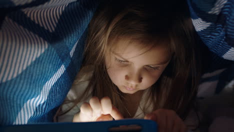 Süßes-Kleines-Mädchen,-Das-Unter-Einer-Decke-Einen-Digitalen-Tablet-Computer-Benutzt-Und-Spaß-Am-Lernen-Auf-Touchscreen-Technologie-Hat,-Indem-Es-Spiele-Spielt-Und-Vor-Dem-Schlafengehen-Spaß-Hat