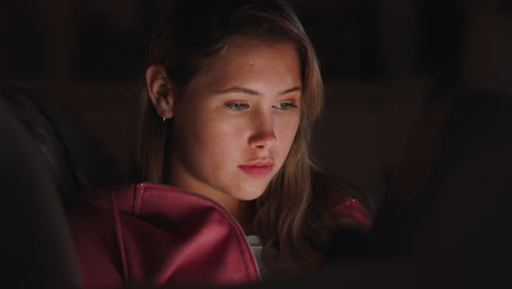 beautiful-teenage-girl-using-tablet-computer-watching-entertainment-at-night-browsing-online-enjoying-relaxing-evening