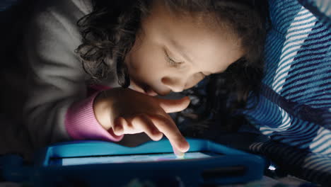 Süßes-Kleines-Mädchen,-Das-Einen-Digitalen-Tablet-Computer-Unter-Einer-Decke-Benutzt-Und-Es-Genießt,-Auf-Der-Touchscreen-Technologie-Zu-Zeichnen,-Spiele-Zu-Spielen-Und-Spaß-Vor-Dem-Schlafengehen-Zu-Haben