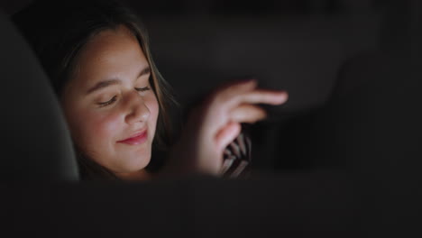Fröhliches-Teenager-Mädchen,-Das-Einen-Tablet-Computer-Nutzt-Und-Sich-Nachts-Unterhaltung-Anschaut,-Indem-Es-Online-Surft-Und-Einen-Entspannten-Abend-Genießt