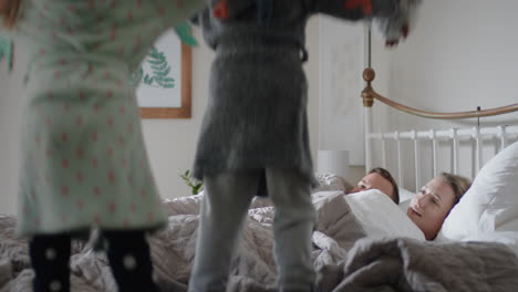 happy-children-jumping-on-bed-waking-up-mother-and-father-enjoying-playful-morning-with-kids