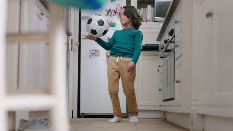 Fröhlicher-Kleiner-Junge,-Der-In-Der-Küche-Mit-Fußball-Spielt-Und-Am-Wochenende-Zu-Hause-Seine-Fähigkeiten-übt