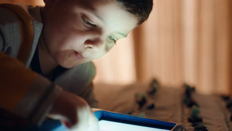 Fröhlicher-Kleiner-Junge,-Der-Einen-Digitalen-Tablet-Computer-Benutzt,-Der-Auf-Dem-Bett-Sitzt-Und-Das-Zeichnen-Genießt,-Auf-Der-Touchscreen-Technologie-Lernt,-Spiele-Spielt-Und-Vor-Dem-Schlafengehen-Spaß-Hat