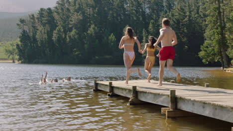 happy-friends-jumping-off-jetty-in-lake-splashing-in-water-enjoying-freedom-having-fun-summer-adventure-on-vacation