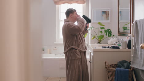 happy-teenage-boy-with-down-syndrome-getting-ready-in-bathroom-using-hair-dryer-enjoying-morning-routine-wearing-bathrobe