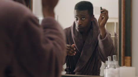 Fröhlicher-Afroamerikanischer-Mann,-Der-Im-Badezimmer-Tanzt-Und-In-Den-Spiegel-Schaut,-Spaß-Am-Morgen-Hat-Und-Sich-Fertig-Macht-Und-Ein-Positives-Selbstbild-Im-Bademantel-Genießt