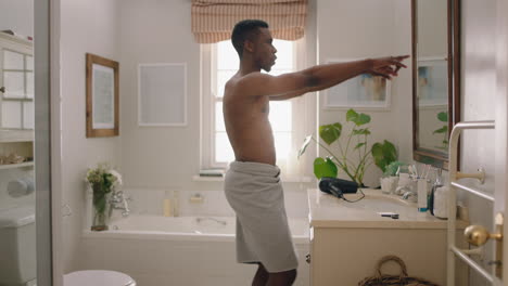 happy-african-american-man-dancing-shirtless-in-bathroom-looking-in-mirror-having-fun-morning-routine-getting-ready-enjoying-positive-self-image-doing-silly-dance-celebrating-success