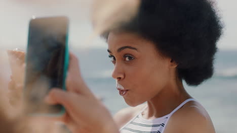 beautiful-woman-with-afro-eating-ice-cream-on-beach-posing-for-friend-taking-photo-using-smartphone-girl-friends-sharing-fun-summer-day-on-social-media-4k