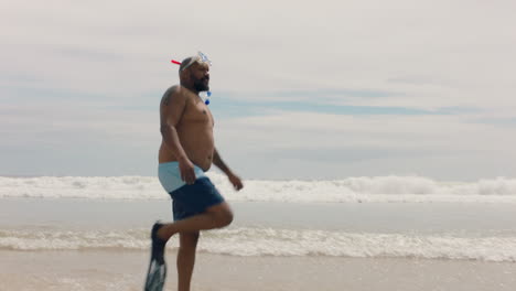 Gracioso-Hombre-Afroamericano-Caminando-Por-La-Playa-Con-Aletas-Preparándose-Para-Nadar-Disfrutando-Del-Verano-Junto-Al-Mar-4k