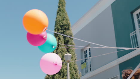 Mädchen-Mit-Bunten-Luftballons,-Das-Auf-Der-Geburtstagsfeier-Der-Stadtstraße-Läuft-Und-Sommerspaß-In-4k-Feiert