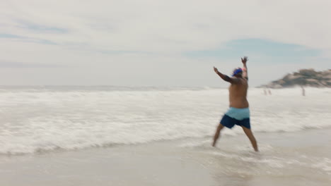 Gracioso-Hombre-Afroamericano-Caminando-Por-La-Playa-En-Agua-De-Mar-Usando-Aletas-Preparándose-Para-Nadar-Disfrutando-Del-Verano-Junto-Al-Océano-4k