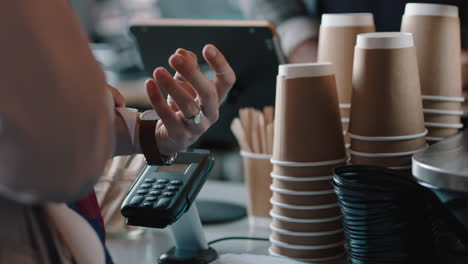 young-african-american-barista-man-serving-customers-in-cafe-using-smart-watch-making-contactless-payment-buying-coffee-spending-money-enjoying-service