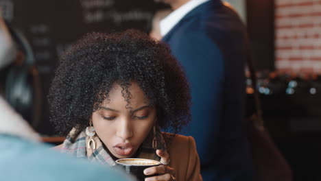 Schöne-Afroamerikanische-Frau-Nutzt-Ihr-Smartphone,-Trinkt-Kaffee-Im-Café-Und-Schreibt-SMS,-Teilt-Nachrichten-In-Sozialen-Medien-Und-Genießt-Mobile-Technologie-In-Einem-Belebten-Restaurant