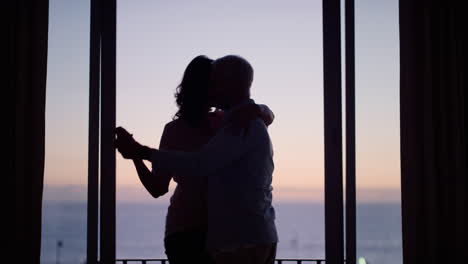 Silhouette-Eines-Glücklichen-Alten-Paares,-Das-Im-Hotelzimmer-Tanzt-Und-Im-Urlaub-Seinen-Jahrestag-Im-Ruhestand-Feiert.-Es-Genießt-Eine-Erfolgreiche-Ehe-Und-Hat-Spaß-Beim-Tanzen-Bei-Sonnenuntergang