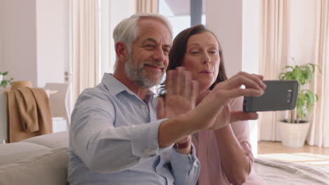 happy-middle-aged-couple-using-smartphone-having-video-chat-blowing-kiss-at-grandchildren-enjoying-online-communication-relaxing-retirement-home