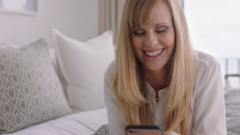 Schöne-Blonde-Frau-Nutzt-Ihr-Smartphone,-Entspannt-Sich-Im-Bett-Und-Schreibt-SMS,-Teilt-Social-Media-Nachrichten-Und-Genießt-Den-Online-Einkauf