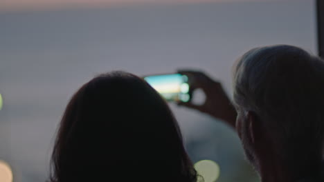 Glückliches-Altes-Paar,-Das-Mit-Dem-Smartphone-Den-Wunderschönen-Sonnenuntergang-Im-Hotelzimmer-Fotografiert-Und-Im-Urlaub-Einen-Erfolgreichen-Ruhestandslebensstil-Genießt-Und-Einen-Romantischen-Urlaub-Teilt