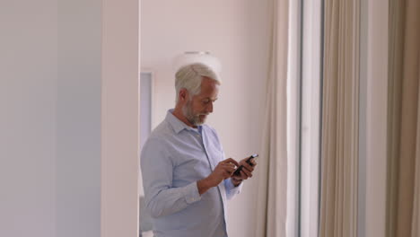 mature-man-using-smartphone-at-home-texting-sharing-messages-on-social-media-enjoying-mobile-phone-communication