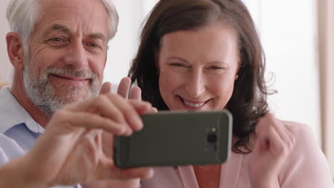 Glückliches-Paar-Mittleren-Alters-Nutzt-Smartphone-Beim-Video-Chat-Und-Bläst-Enkelkindern-Einen-Kuss-Zu-Und-Genießt-Die-Online-Kommunikation-Und-Entspannt-Sich-Im-Altersheim