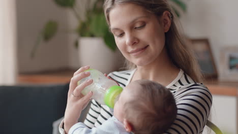 Madre-Feliz-Alimentando-Al-Bebé-Bebiendo-De-Una-Botella-De-Leche-Mamá-Amorosa-Cuidando-Al-Bebé-Disfrutando-De-La-Maternidad-Relajándose-En-Casa