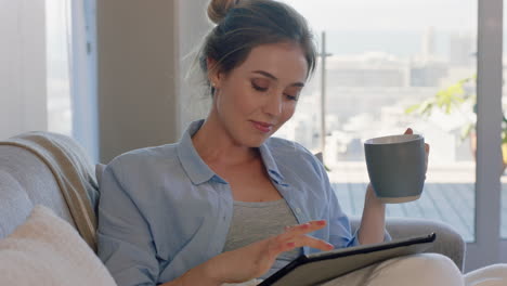 beautiful-young-woman-using-digital-tablet-computer-relaxing-on-couch-at-home-browsing-online-drinking-coffee-enjoying-comfortable-lifestyle