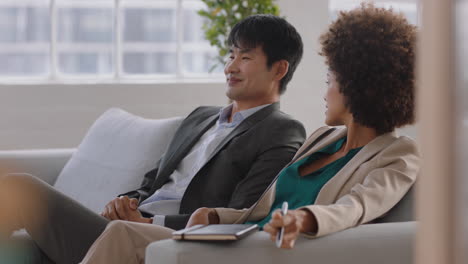 business-people-talking-african-american-woman-chatting-to-asian-colleague-having-conversation-relaxing-on-couch-in-office-enjoying-connection