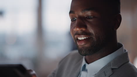 Junger-Afroamerikanischer-Geschäftsmann,-Der-Spät-Im-Büro-Arbeitet-Und-Einen-Tablet-Computer-Nutzt,-Um-Informationen-Zu-Durchsuchen-Und-Daten-Auf-Einem-Digitalen-Touchscreen-Anzusehen