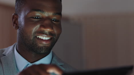 Junger-Afroamerikanischer-Geschäftsmann,-Der-Spät-Im-Büro-Arbeitet-Und-Einen-Tablet-Computer-Nutzt,-Um-Informationen-Zu-Durchsuchen-Und-Daten-Auf-Einem-Digitalen-Touchscreen-Anzusehen