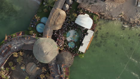Festival-at-tropical-Beach-Club-Party-with-crowd-dancing-and-having-a-good-time,-Aerial-Birds-Eye-Overhead-Top-Down-View