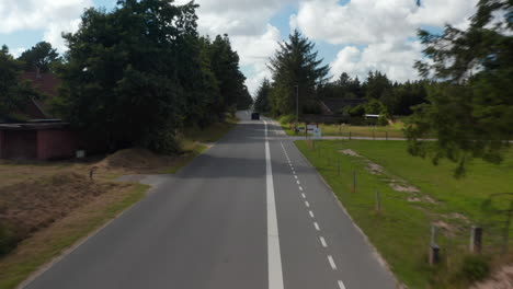 Vorwärtsflug-über-Straße-Mit-Radweg,-Der-Durch-Landschaft-Mit-Bäumen-Und-Häusern-Führt.-Autofahren-Auf-Der-Straße.-Dänemark