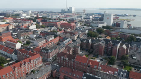 Forward-slow-flight-through-Esbjerg,-Denmark,-neighborhood-with-characteristic-brick-building.-Bird's-eye-view-revealing-the-chimney-of-the-coal-and-oil-fueled-power-plant-near-the-harbour