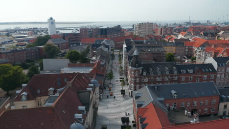 Aerial-view-of-Torvegade,-one-of-Denmark's-longest-pedestrian-streets,-in-Esbjerg.-Top-down-view-of-the-downtown-of-the-city-with-characteristic-brick-building-and-pedestrian-strolling-and-shopping