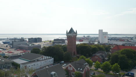 Drone-slow-camera-rotation-around-the-Water-Tower-of-Esbjerg,-Denmark,-an-iconic-water-tower-at-the-top-of-a-cliff-overlooking-the-most-important-harbor-of-north-sea