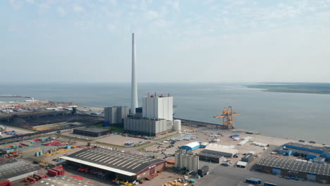 Birds-eye-slowly-rotating-around-the-chimney-of-Steelcon-power-station-in-Esbjerg,-Denmark.-Aerial-drone-view-of-coal-and-oil-fueled-power-plant-with-the-tallest-chimney-of-Scandinavia