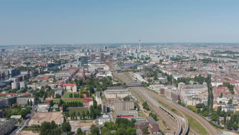 Aerial-view-of-main-railway-track-leading-through-large-city.-Fernsehturm-TV-tower-in-distance.-Berlin,-Germany