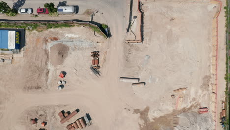 Aerial-birds-eye-overhead-top-down-view-of-construction-site.-Descending-footage-of-dirty-and-dusty-place-of-future-new-building.-Berlin,-Germany
