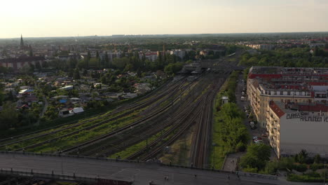 Aerial-view-of-multi-track-railway-line-in-town.-Fly-above-residential-buildings.-Panoramic-view-of-large-city-in-late-evening-sunshine.-Berlin,-Germany