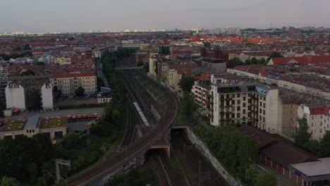 Aerial-view-of-regional-train-driving-on-railway-tracks-between-residential-tenement-houses-in-city.-Berlin,-Germany