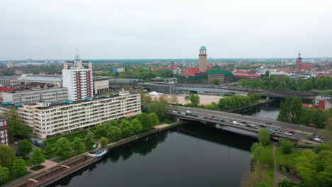 Aerial-footage-of-busy-multilane-road-on-bridge-over-water-and-apartment-buildings-on-Havel-river-waterfront.-Town-hall-tower-in-background.-Berlin,-Germany