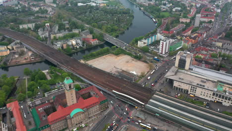 Aerial-shot-of-Havel-river-flowing-through-town-near-Rathaus-Spandau.-High-angle-view-of-traffic-around-train-station.-Berlin,-Germany