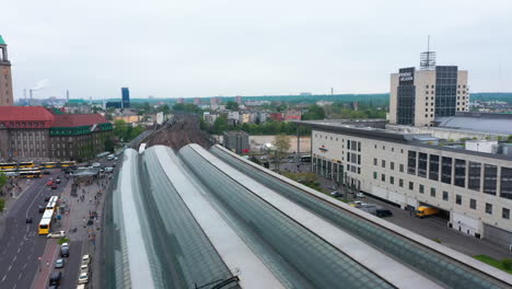 Forwards-fly-above-platform-sheds-on-train-station.-Road-traffic-around-shopping-mall.-Town-development-in-background.-Berlin,-Germany