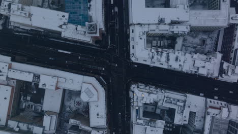 Aerial-birds-eye-overhead-top-down-ascending-footage-of-trams-passing-through-road-intersection-between-snow-dusted-buildings-in-city-centre.--Berlin,-Germany