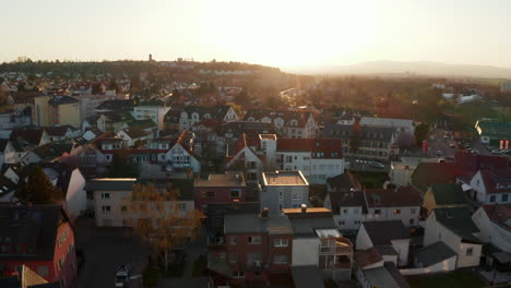 Aerial-drone-view-of-houses-and-streets-in-spa-town.-View-against-setting-sun-in-evening-golden-hour.-Bad-Vilbel,-Germany.