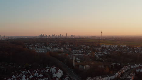 Aerial-evening-view-on-Frankfurt-am-Main-city-panorama-from-distance.-Drone-flying-above-small-town-neighbourhood.-Bad-Vilbel,-Germany.