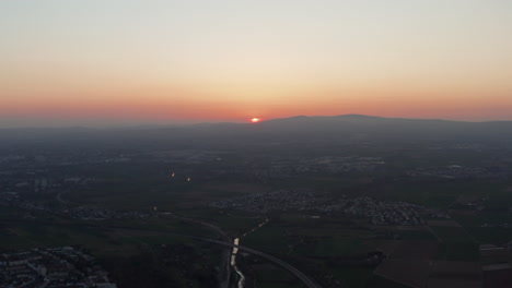 Aerial-evening-flat-landscape-view.-Setting-sun-behind-horizon.-View-from-drone-flying-above-small-town.-Colourful-twilight-sky.