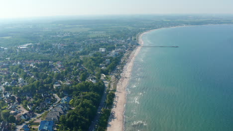 High-aerial-drone-view-of-scenic-summertime-beach-in-Scharbeutz,-Germany,-dolly-in,-sunny-windy-day