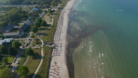 Majestic-aerial-drone-view-of-travel-destination-tourist-beach-at-Baltic-sea-in-Scharbeutz,-Germany,-dolly-in-tilt-down,-day
