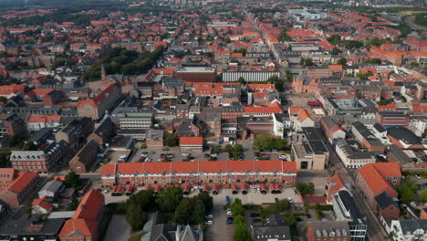 Aerial-birds-eye-of-city-street-neighborhood-in-Esbjerg,-Denmark.-Overhead-top-down-slow-view-on-a-neighborhood-with-pedestrian-strolling-down-the-road-and-car-parked-in-parking-lot