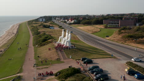 Vista-Aérea-De-La-Costa-De-Esbjerg,-Con-Rotación-Lenta-De-La-Cámara-Alrededor-Del-Hombre-Que-Se-Encuentra-Con-La-Escultura-Del-Mar.-Vista-De-ángulo-Alto-De-La-Famosa-Escultura-Od-Con-Muchos-Turistas-Visitando.-Esbjerg,-Dinamarca